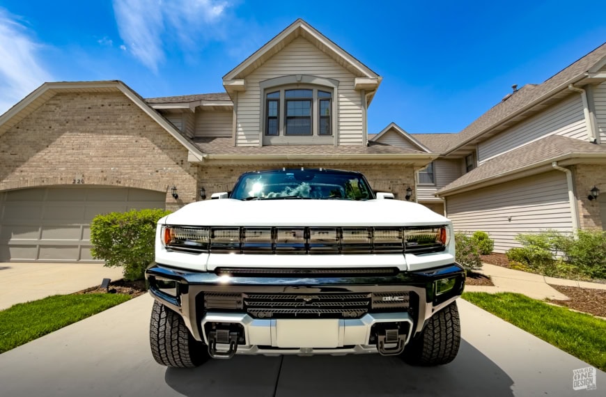 All-electric 2024 Hummer EV SUV parked in front of a modern house, showcasing its bold design and advanced features.