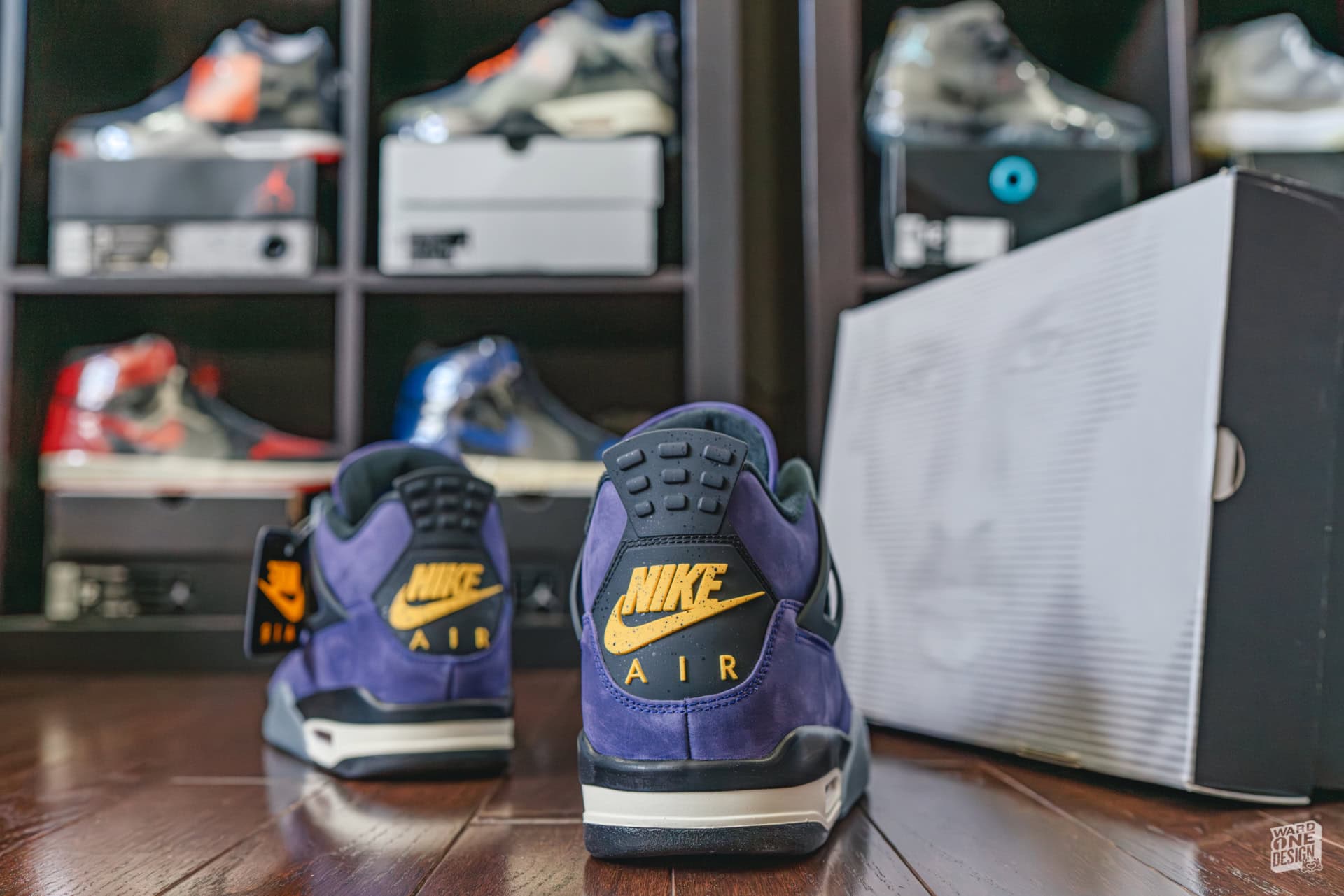 Air Jordan 4 Lakers sneakers with purple and gold colorway, displayed on a wooden floor in front of a sneaker display shelf. Perfect for basketball fans and sneaker collectors.