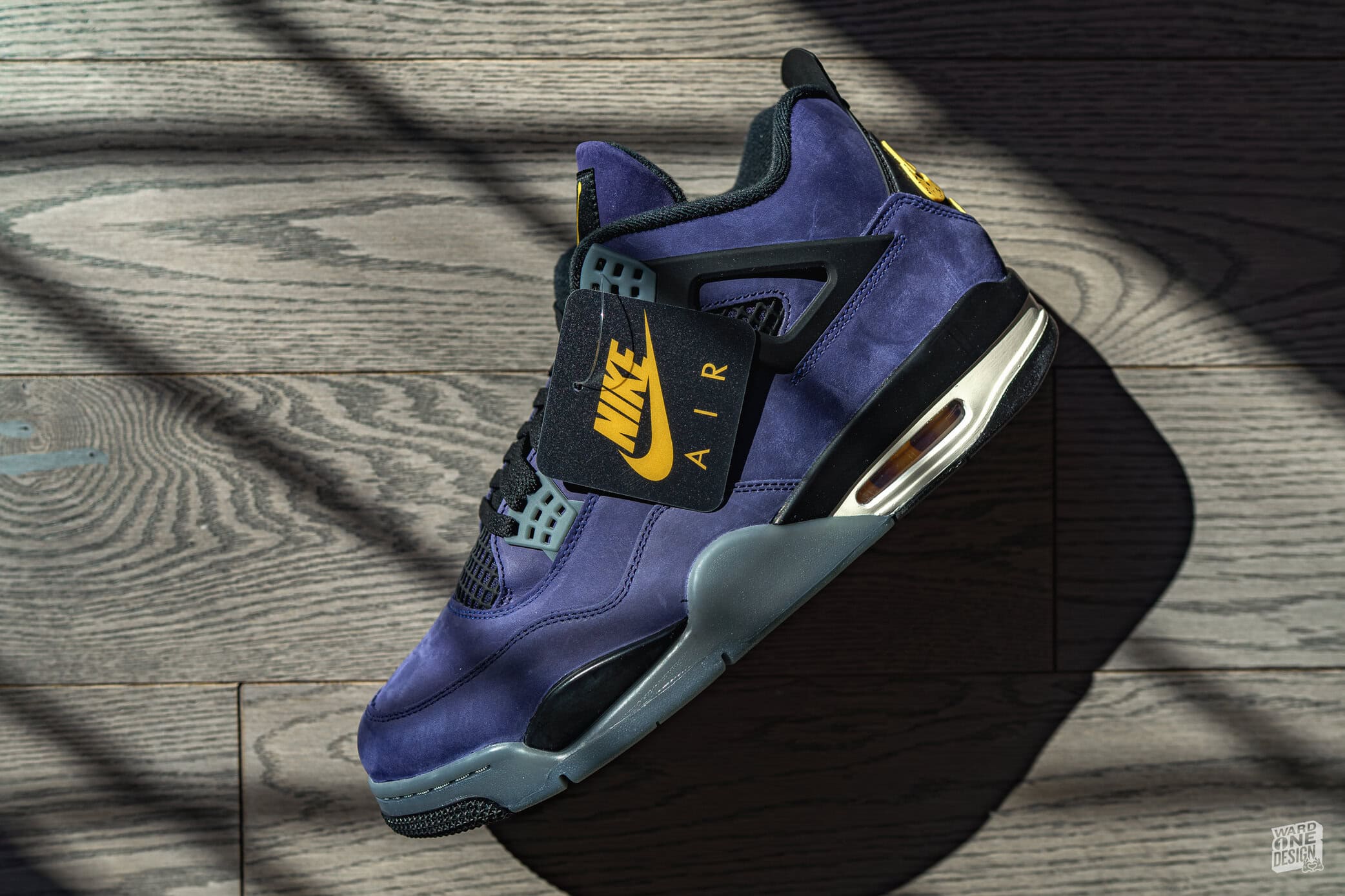 Close-up of Air Jordan 4 Lakers sneakers in purple and gold, highlighting the iconic design and Lakers colorway on a wooden floor. Perfect for sneaker enthusiasts and basketball fans.