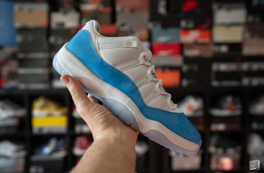 Close-up of Air Jordan 11 Retro Low UNC sneaker held in hand, showcasing the iconic white and University Blue colorway, perfect for sneaker enthusiasts and collectors.