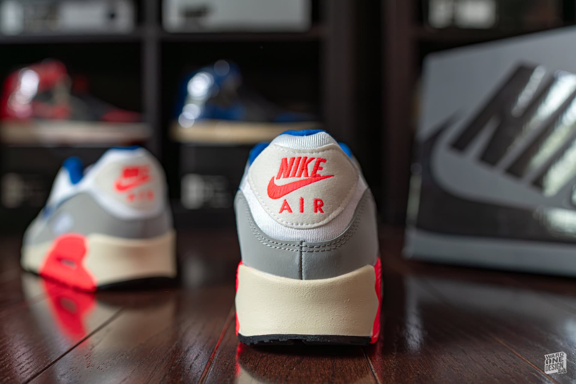 Nike Air sneakers with red, white, and gray color scheme, showcased on a wooden surface in a sneaker shop.
