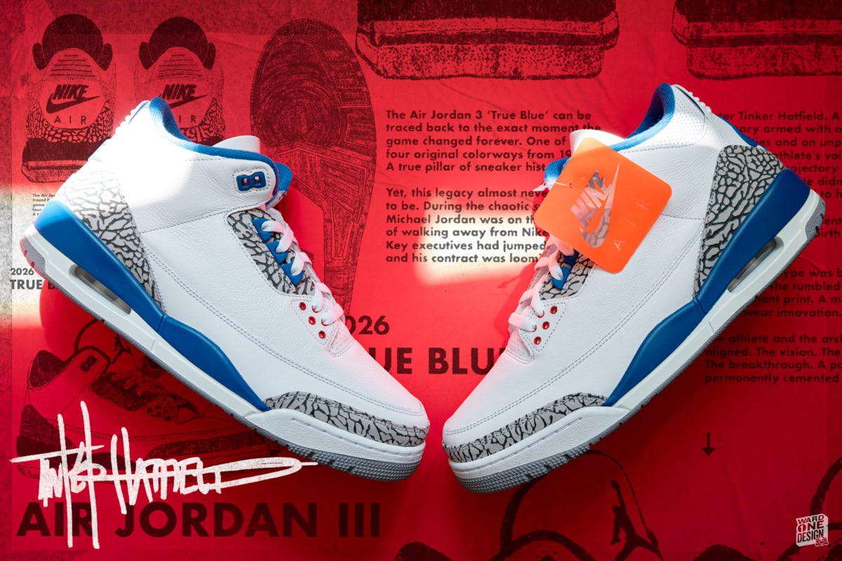 Close-up of Nike Air Jordan 3 Retro sneakers with white, blue, and gray design, displayed on red background with Nike branding and product tags.