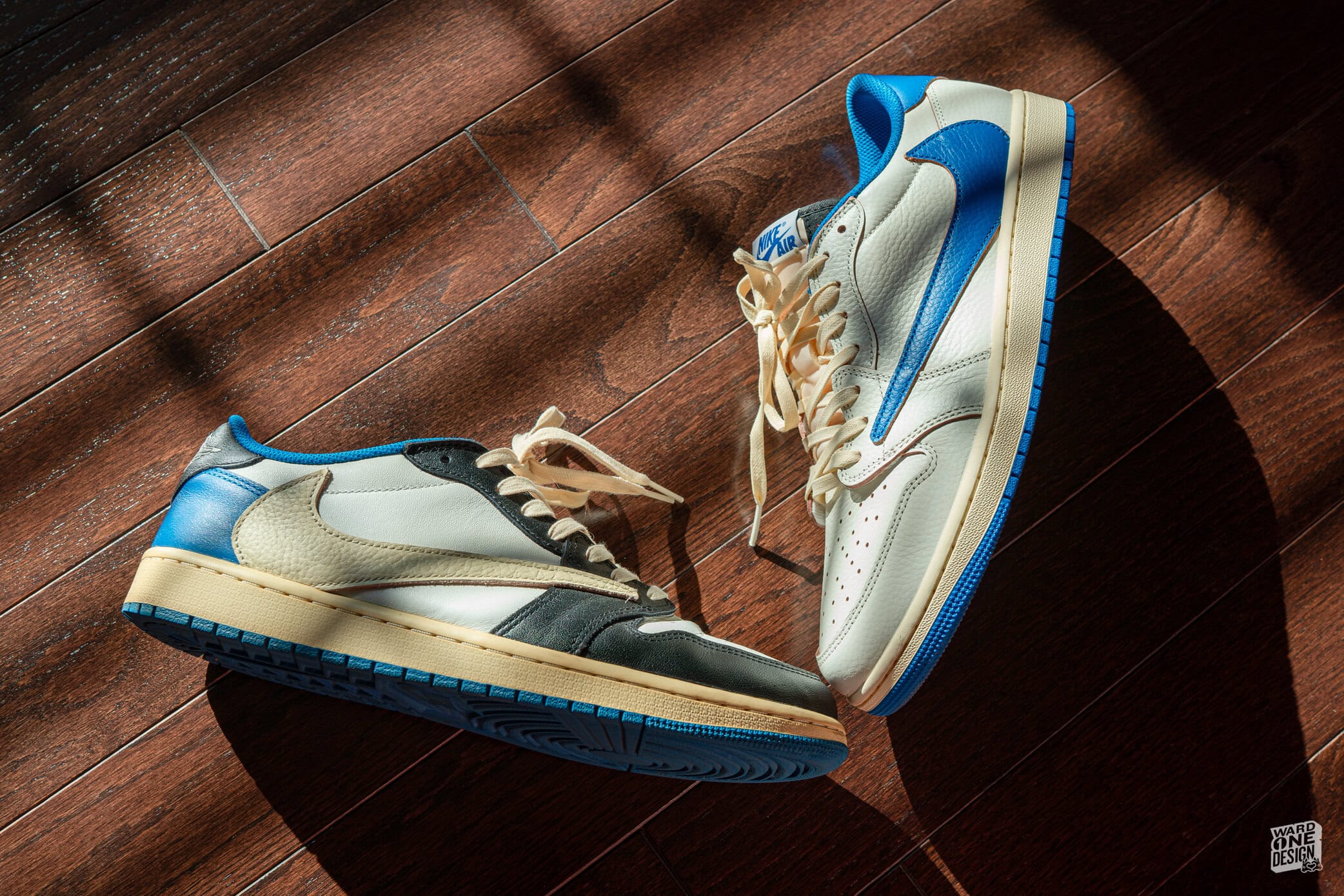 Close-up of Air Jordan 1 Low OG SP Travis Scott x Fragment sneakers on wooden floor, showcasing design and color details.