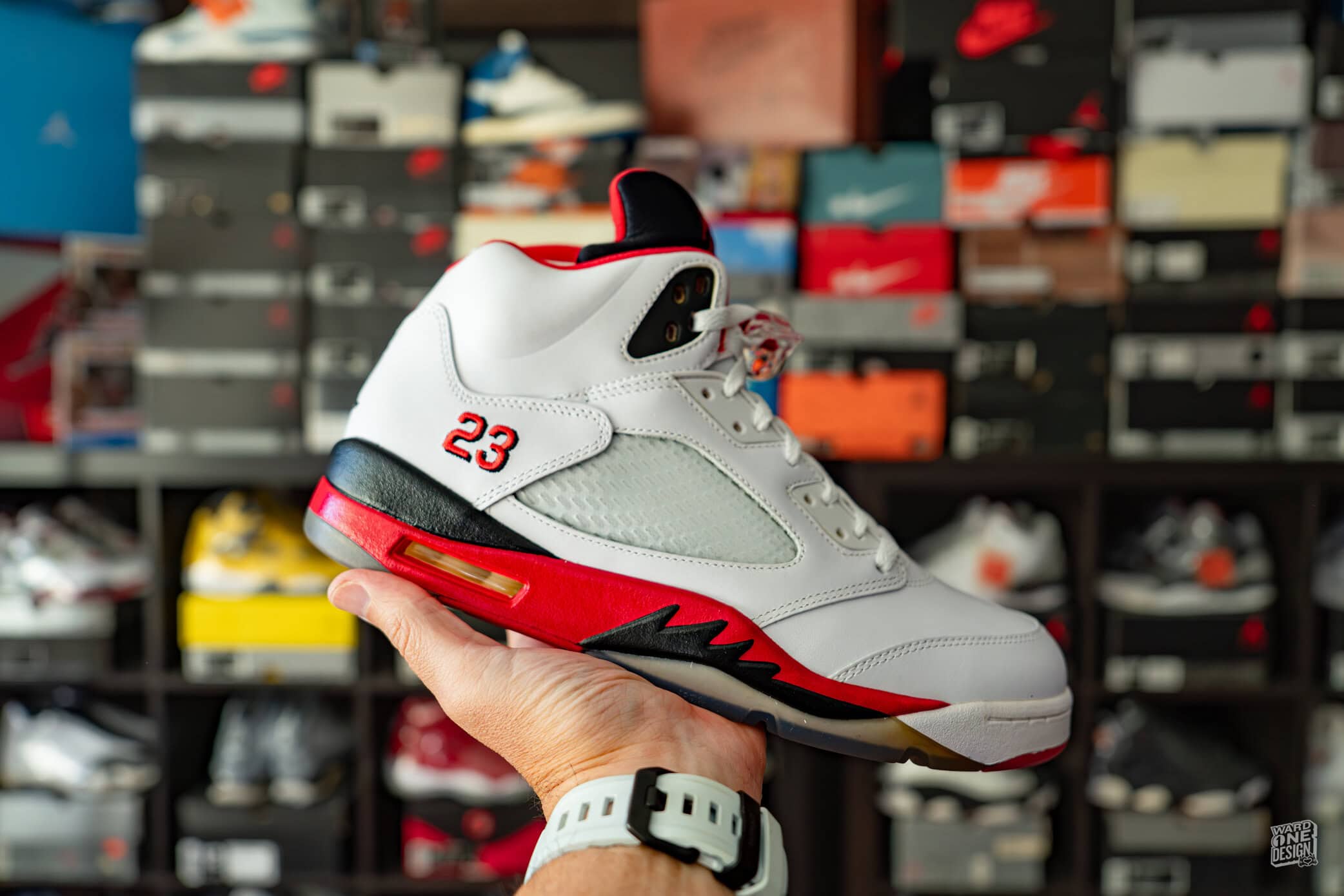 Air Jordan 5 Fire Red sneaker with white, red, and black accents, featuring the number 23 on the side, showcased in a sneaker store. Perfect for collectors and basketball fans.