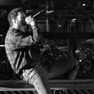 Post Malone singing passionately on stage during the stadium concert.