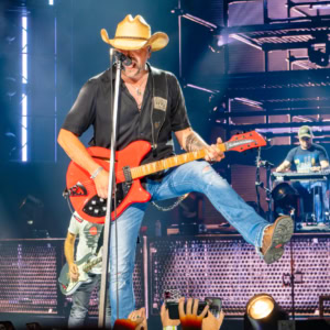 Jason Aldean on stage during the Full Throttle Tour, showcasing his country music performance with a cowboy hat and vibrant stage lighting.