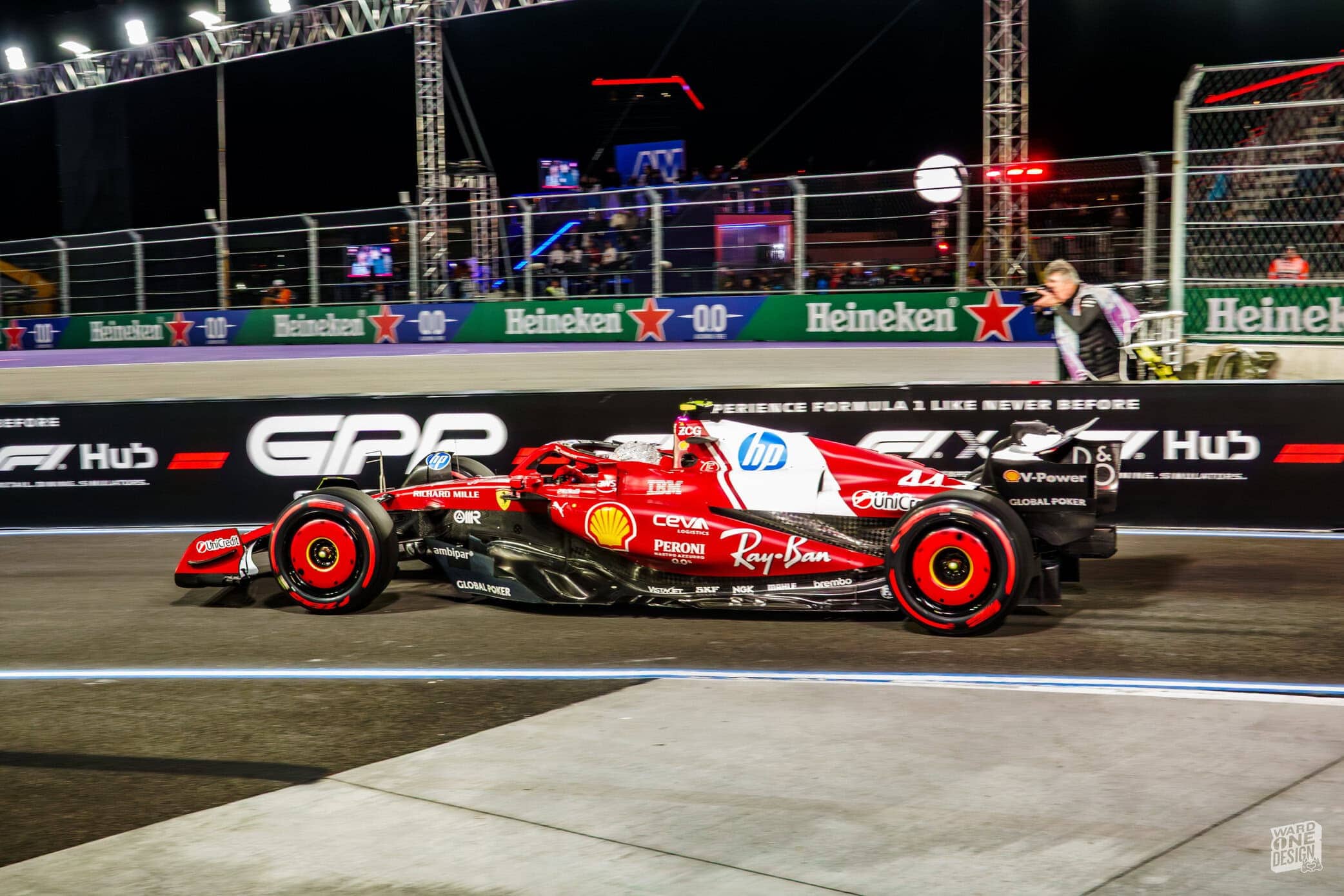 Formula 1 Race Car at Night Red and black Formula 1 race car on track during night race, with team branding and sponsor logos visible, illuminated by track lighting.