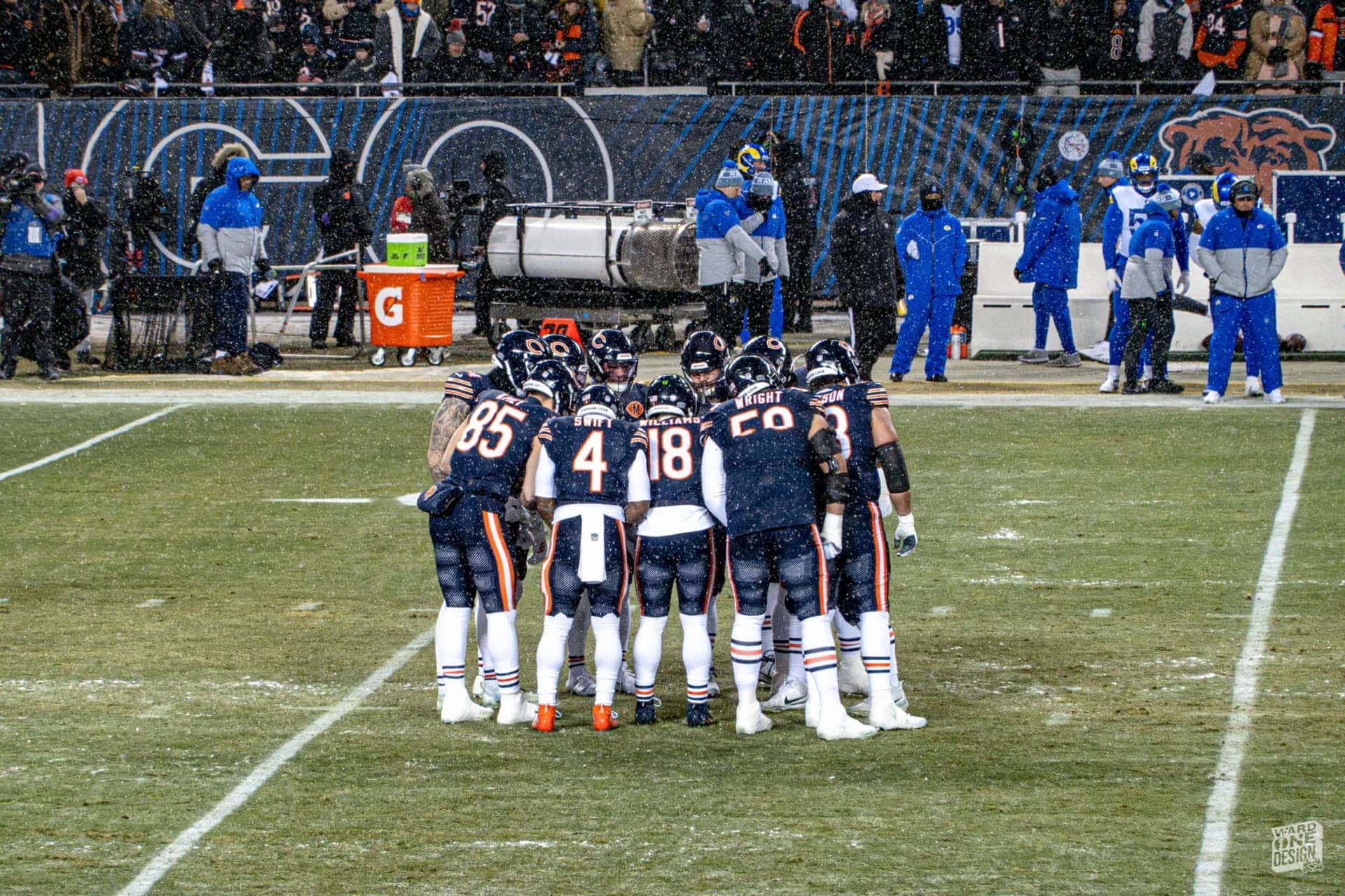 Chicago Bears Football Team Huddle Chicago Bears football team huddling on the field during a game, with players in navy blue uniforms and white helmets, coaches, and staff in the background.