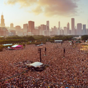 Crowd at Lollapalooza 2025 festival with Chicago skyline in the background, showcasing a vibrant music event with thousands of attendees enjoying live performances in an outdoor urban setting.